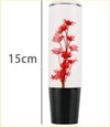 A sleek 15cm red hana gear knob vase with black base silver rim and vibrant red preserved flowers in clear resin
