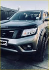 Silver nissan navara pickup with black aftermarket nismo grill and rugged off-road tires