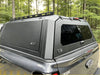 Gray aluminium hardtop canopy with tinted rear window and black roof rack on the back of a ford ranger 2022+