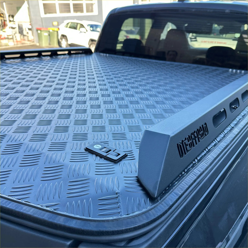 Gray diamond plate aluminium hard lid truck bed cover with sleek rugged design and embossed branding for mazda bt-50 double cab back side