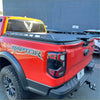 Red ford ranger raptor pickup truck back with black textured aluminum hard lid tonneau cover and raptor decals