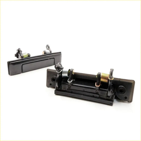 Black plastic door handle set for Toyota Hilux ute 1984-1988 showing back with spring mechanism and mounting hardware