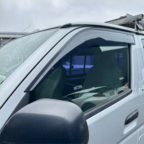 Black plastic door visor installed on a silver toyota hiace for weather protection and aftermarket style