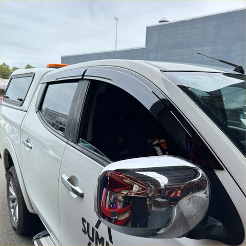 Black plastic door visors weather shields installed on white mitsubishi triton pickup truck windows