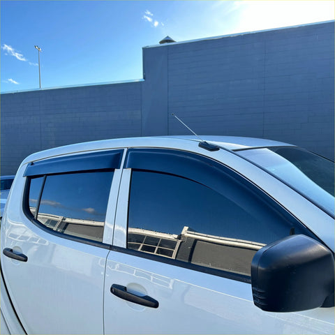 Black plastic door visors weather shields installed on white mitsubishi triton for window monsoon protection