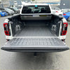 Black textured rubberized electric roller shutter tonneau cover with integrated tailgate and cargo tray on white ford ranger