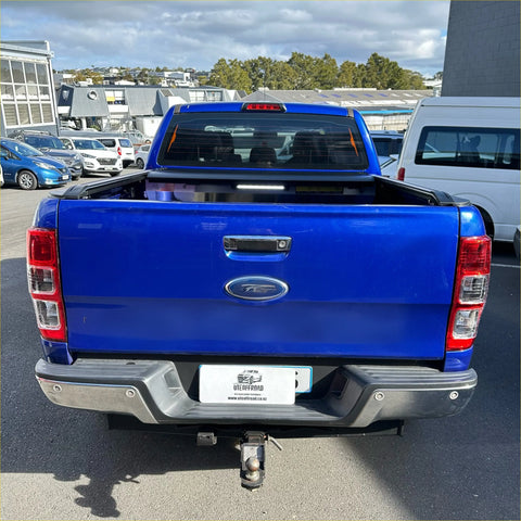 Vibrant blue ford ranger pickup with black electric roller tonneau cover and chrome accents shown from the back side