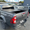 Gray toyota hilux pickup truck with a black electric roller shutter tonneau cover on the back side of the bed