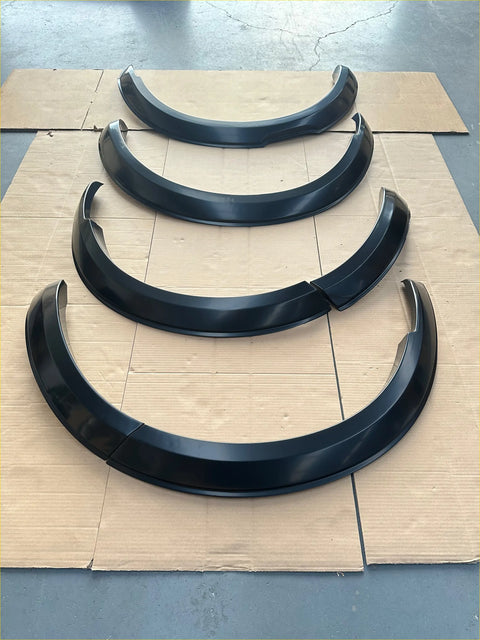 Black glossy 4 inch fender flares for Nissan Navara 2021 plus arranged on cardboard in descending size