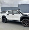 White toyota hilux with matte black lychee texture bolt style fender flare and black aftermarket body kit and roof rack