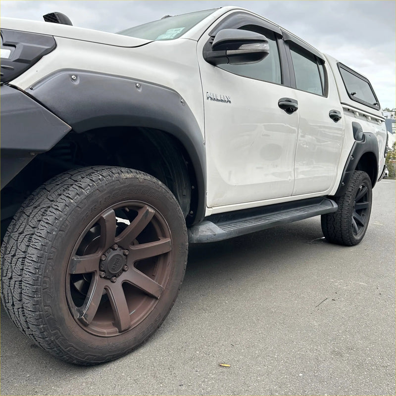White toyota hilux rocco 2018-2020 with black lychee texture fender flares and roof rack from the back side