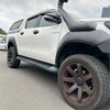 White toyota hilux with black lychee texture fender flares and matte brown wheels shown from the front side