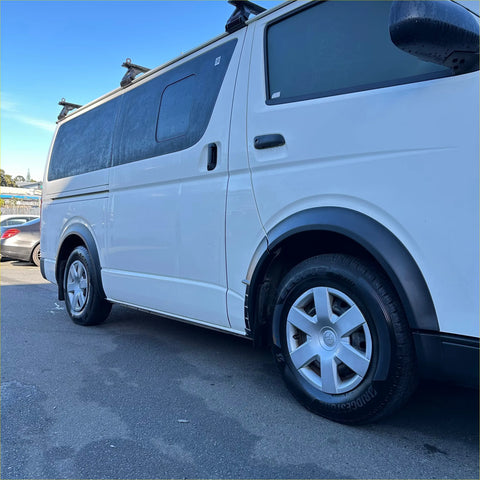 White toyota hiace van with matte black sport style fender flares, black trim, and roof racks from 2005-2019 model