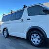 White toyota hiace van with black matte sport style fender flares black roof racks and tinted windows side view
