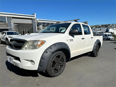 White toyota hilux vigo 2012-2015 with black bolt style textured fender flares and alloy wheels front side view