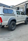 Silver toyota hilux pickup with bolt style textured black fender flares and rugged off-road tires