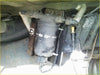 Black cylindrical fuel filter with dzus quick release housing and attached hoses for land rover under vehicle use