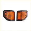 A pair of front corner indicator lights with black frames and amber textured lenses for vehicle signaling