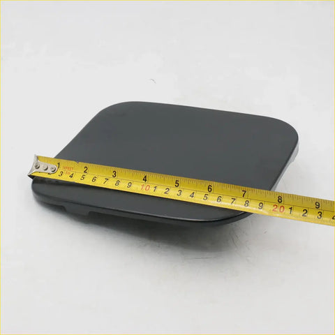 Black rectangular gas door fuel lid cover for Toyota Hilux with matte finish and yellow measuring tape on top