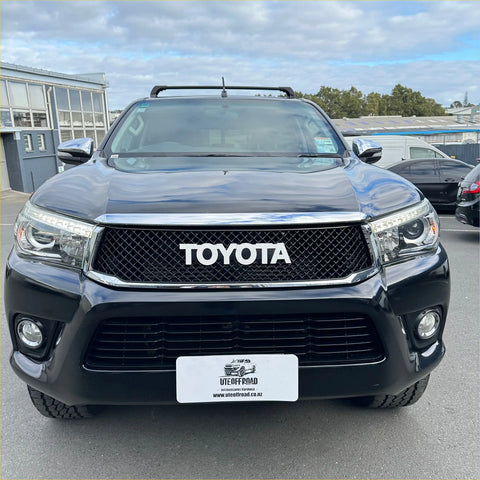 Black Toyota Hilux 2015-2020 with chrome grille and roof rack showing front of the pickup truck