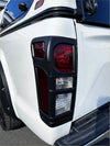 Black plastic taillight cover with red and clear lenses mounted on white isuzu d-max 2016-2020 pickup truck