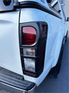 Black plastic tail light assembly with red amber and clear lenses on white isuzu d-max 2016-2020 pickup back side