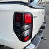 Black plastic tail light cover with red and clear lenses mounted on white mitsubishi triton 2019-2023 pickup truck
