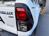 Back view of white toyota hilux sr pickup with black plastic taillight covers for 2021-2024 sr sr5 models