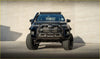 Black toyota pickup truck with rugged off-road kenda klever mt2 tires 35x12.5 r17 and roof light bar visible