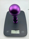 Purple metallic Kobe billet gear knob with spherical top and cylindrical stem resting on a digital scale