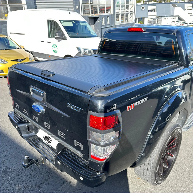 Black ford ranger xlt pickup with manual roller shutter hirider tonneau cover shown from the back side