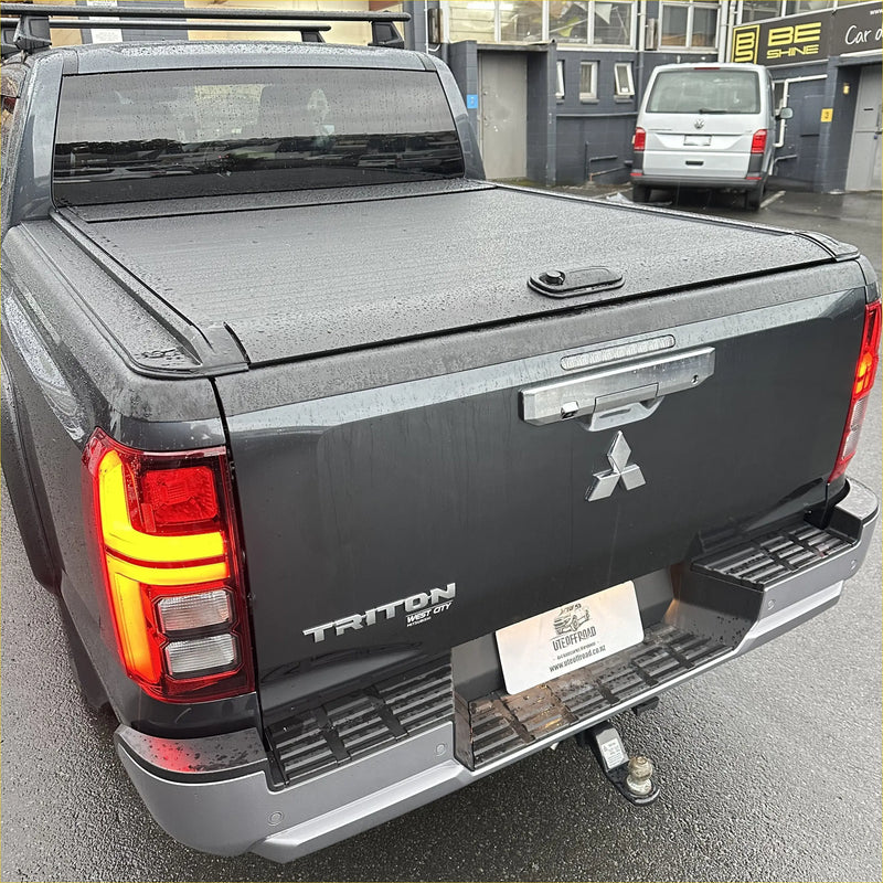 Black manual roller shutter tonneau cover on the back of a mitsubishi triton 2024+ pickup truck