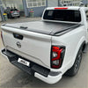 White nissan navara pickup truck with black manual roller shutter tonneau cover shown from the back side