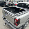 Back view of gray ford ranger sport pickup with a black manual roller shutter tonneau cover for vw amarok 2023+
