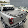 Gray retractable manual roller shutter tonneau cover on the back side of a ford ranger pickup truck for volkswagen amarok 2023+