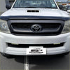White toyota hilux pickup truck with black front grille and chrome emblem featuring monsoon and bonnet guard