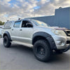 Silver toyota hilux with matte black monster flare bolt style fender flares and off-road tires for 2012-2015 models