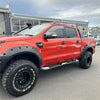Vibrant red ford ranger px1 wildtrak with bolt style matte black monster flare fender flares and rugged off-road tires