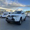 White mitsubishi triton pickup with matte black nudge bar compatible with front sensors and roof rack from 2005 to 2015