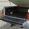 Black rubberized textured bed liner with circular footrests and metal brackets for rear tailgate assist struts on 4wd ute