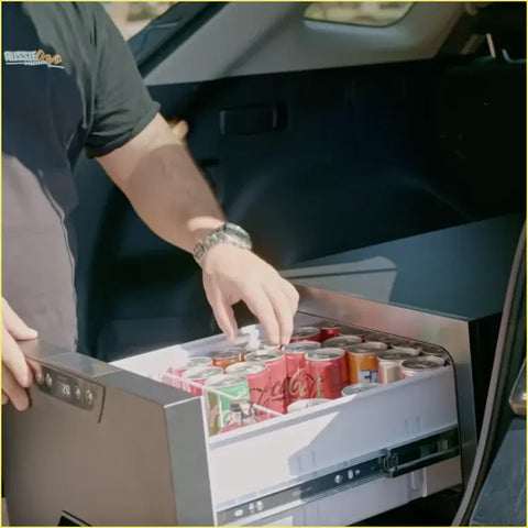 Silver-framed rockarmor 31 litre vehicle draw fridge with digital display and sliding drawer full of soda cans for 4wd ute offroad use