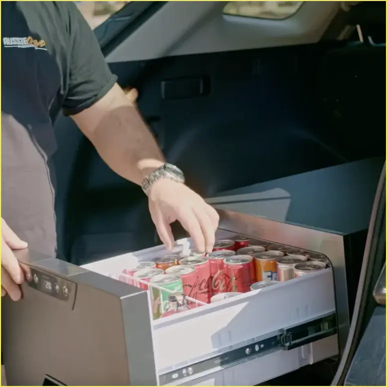 Silver-framed rockarmor 31 litre vehicle draw fridge with digital display and sliding drawer full of soda cans for 4wd ute offroad use