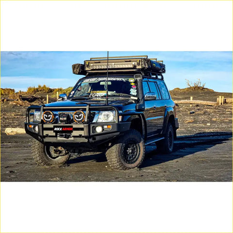 Black nissan patrol 4wd with rockarmor brushbar gt bullbar rugged tires and roof rack carrying camping gear offroad