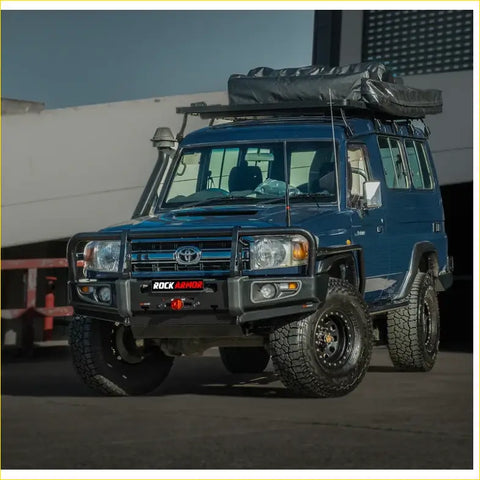 Deep blue toyota land cruiser with black rockarmor brushbar front bumper and roof rack tent for offroad 4wd use