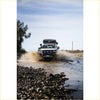 White toyota hilux ute with black roof rack and rockarmor gt steel hoop bullbar splashing through shallow water offroad 4wd