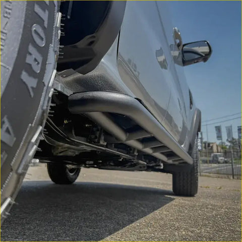Black tubular steel rockarmor rockslider side steps on silver ford ranger nextgen 22+ ute for offroad 4wd protection