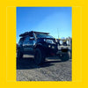 Black nissan navara np300 d23 with rugged roof rack and dual round headlights featuring rockarmor steel rockslider side steps