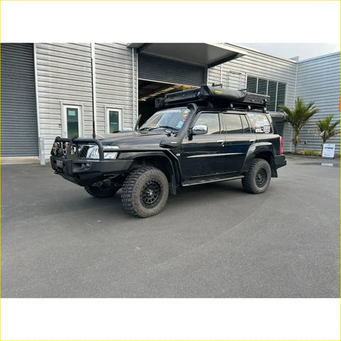 Black Rockarmor steel rockslider side steps on Nissan Patrol Y62 2010-2013 V8 with rugged offroad 4wd tires and roof rack