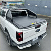 Black roll-up tonneau cover on white ford ranger pickup truck shown from the back with roll bar t20 and manual roller shutter
