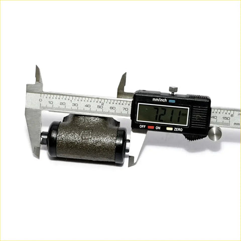 Black and silver digital caliper measuring dark gray textured rr wheel brake cylinder for mitsubishi tredia sedan 1982-1990